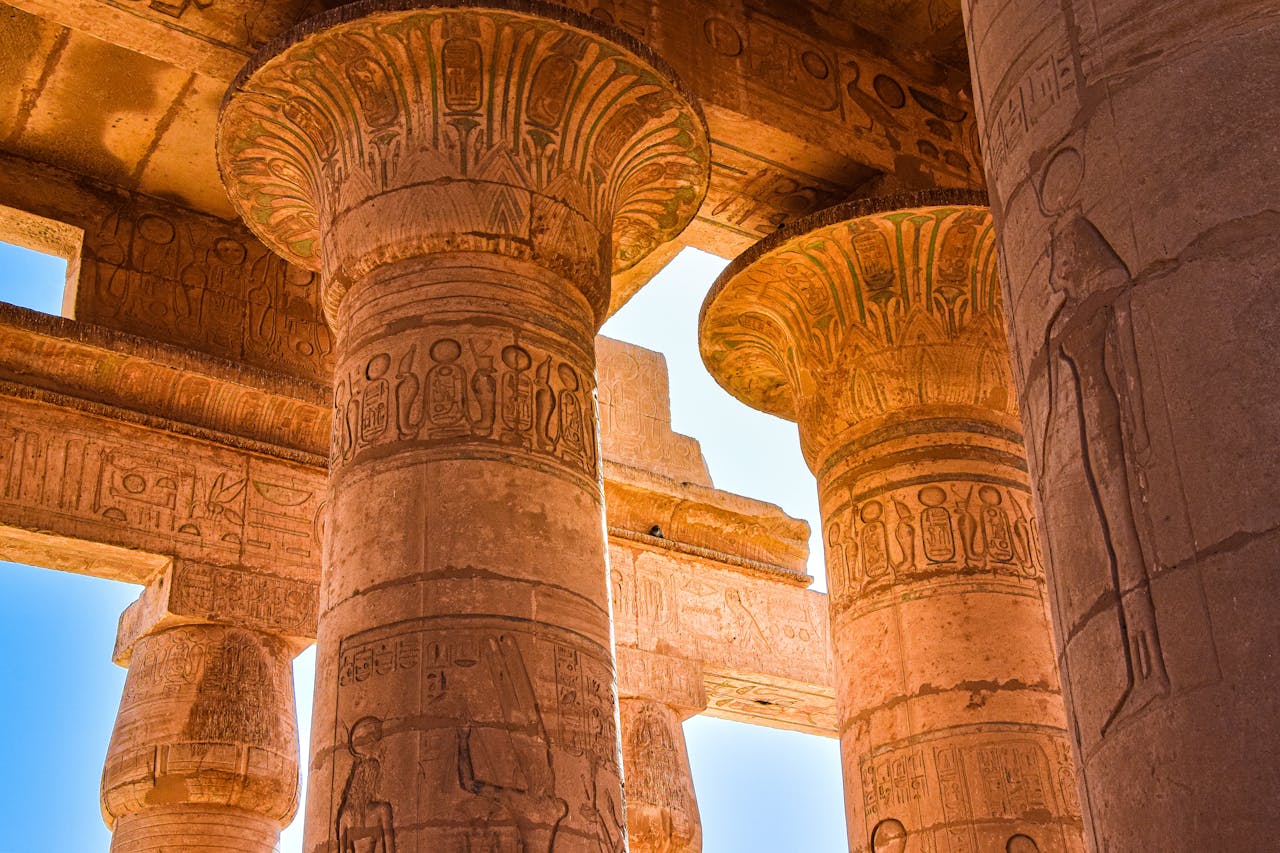 Close-up view of ancient Egyptian temple columns with hieroglyphics under daylight.
