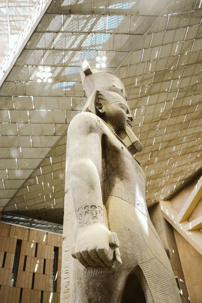 Side view of a colossal pharaoh statue inside Cairos Grand Egyptian Museum.